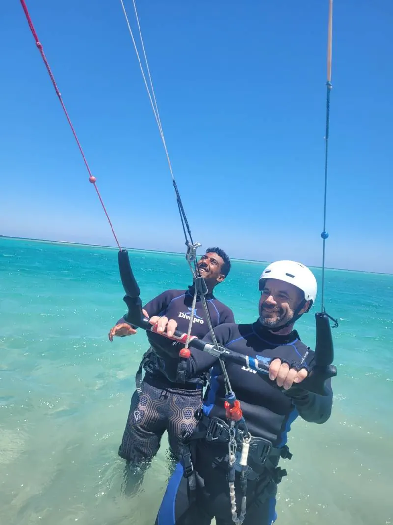 Instructor helping a guest hold the kite bar in shallow water